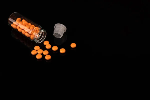 One glass jar of yellow Valerian pills on black background — Fotografia de Stock