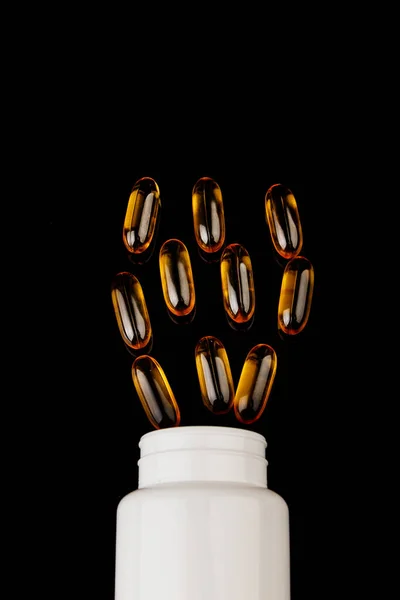 Omega-3 kapslar med svart bakgrund. Hälsokoncept med fiskoljekapslar. Vit flaska — Stockfoto