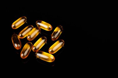 Capsules with fish oil on a black background. The use of vitamin D, omega-3. Health concept