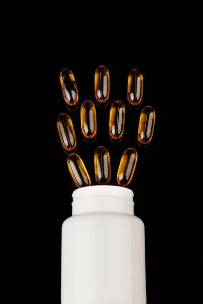Hälsosam kost koncept. Fiskolja kapslar med omega 3 och vitamin D i en plastflaska på en svart bakgrund. — Stockfoto