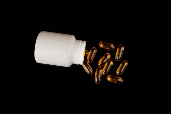 Healthy diet concept. Fish oil capsules with omega 3 and vitamin D in a plastic bottle on a black background. — Fotografia de Stock