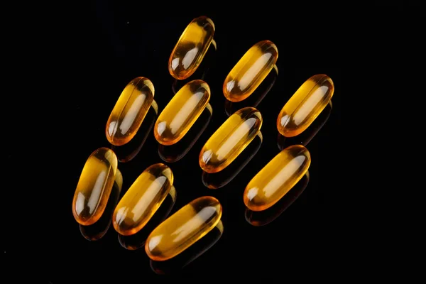 Capsules with fish oil on a black background. The use of vitamin D, omega-3. Health concept — Stockfoto