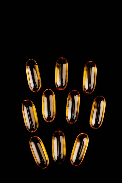 काळ्या पार्श्वभूमीवर फिश ऑईलसह कॅप्सूल. व्हिटॅमिन डी, ओमेगा-3 चा वापर. आरोग्य संकल्पना — स्टॉक फोटो, इमेज