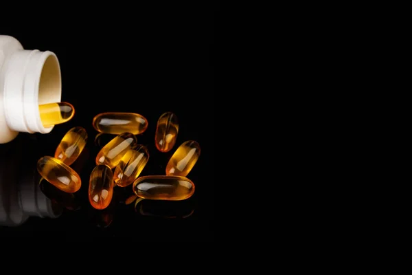 Omega-3 capsules on a black background. Health concept with fish oil capsules. White bottle — Fotografia de Stock