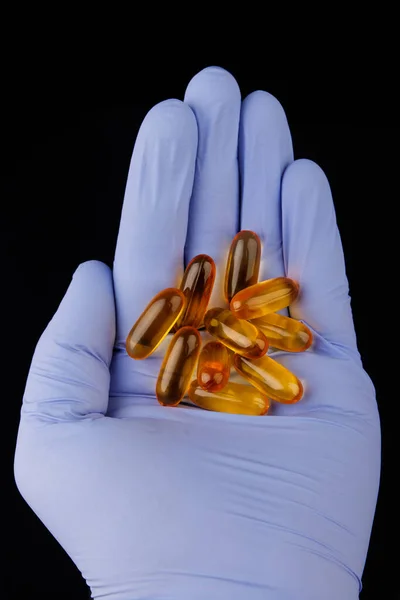 Omega-3 kapslar i hand med medicinsk handske. Hälsokoncept med fiskoljekapslar. — Stockfoto