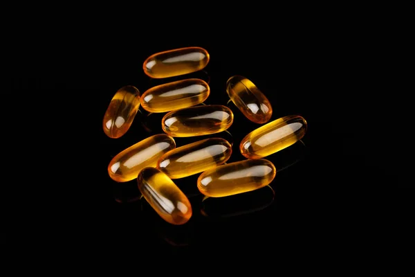 Omega-3 capsules on a black background. Health concept with fish oil capsules. Stock Image