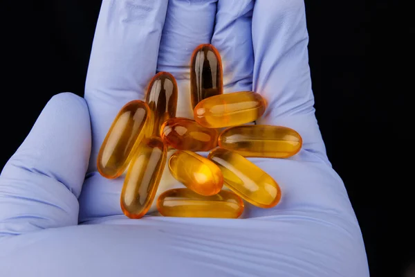 Omega-3 capsules in hand with medical glove. Health concept with fish oil capsules. Royalty Free Stock Photos