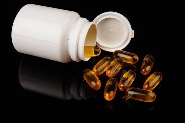Omega-3 capsules on a black background. Health concept with fish oil capsules. White bottle Royalty Free Stock Images