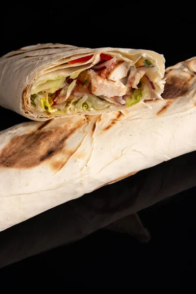 Classic shawarma kebab pita with chicken and vegetables and sauce on a black background. in section Stock Image
