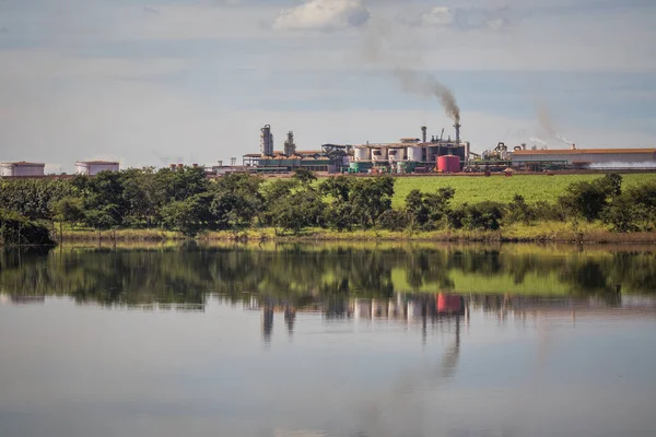 Sugarcane processing plant in operation, with dam in the foreground in the interior of Goias, Brazil