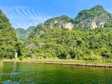 Tam Coc 'ta bambu çitleri olan nehir kenarındaki görkemli kireçtaşı dağları, Ninh Binh. Bu fotoğraf Tam Coc - Bich Dong Trang An Peyzaj Kompleksi 'nde çekildi - Ninh Hai, Hoa Lu, Ninh Binh, Vietnam 17 Aralık 2025.
