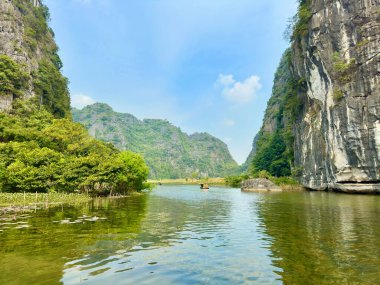 Huzurlu Ngo Dong nehri. Küçük kayıklar turistleri dalgalanan yeşil kireçtaşı dağları arasında taşır. Tam Coc - Bich Dong Trang An Peyzaj Kompleksi içinde yakalandı - Ninh Hai, Hoa Lu, Ninh Binh, Vietnam, 17 Aralık 2025.