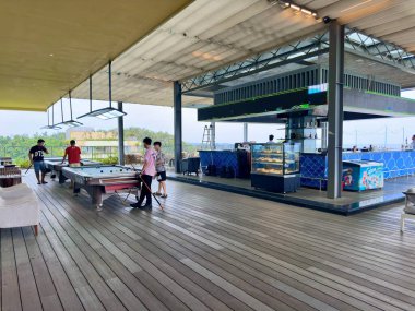Bilardo masaları ve Flamingo Cat Ba 'da bir açık hava barı olan hareketli bir eğlence alanı. Fotoğraf, çatıda bilardo oynayan bir grup genç turisti mavi LED ışıklandırmalı modern bir içecek tezgahının yanında yakalıyor. Yakalandı.
