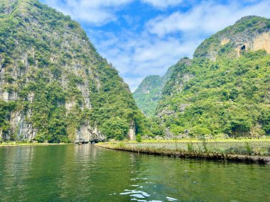 Tam Coc Vadisi 'nin panoramik manzarası. Dikey uçurumlar görkemli doğal manzaranın ortasında duruyor. Karakteristik kireçtaşı kütleleriyle 
