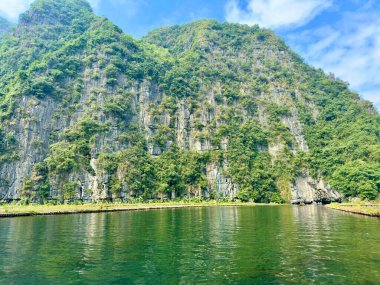 Zümrüt yeşili nehrin kıyısına yansıyan kireçtaşı kayalıklarının eşsiz jeolojik yapılarını kapatın. Uçurumdaki taş damarlar ve doğal oyuklar Dünya 'nın tarihini anlatır. Tam Coc - Bich Dong, Ninh Binh, Vietnam, 10 Aralık,