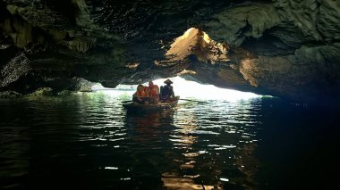 Yabancı turistlerin Ninh Binh vilayetindeki teknelerle mağaraları gezip keşfe çıktığı bir an. Bir grup turist teknede mağaranın içindeki muhteşem güzelliği keşfediyorlar. Tam Coc - Bich Dong, Ninh Binh, Vietnam, Decembe