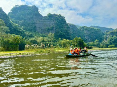Ngo Dong nehri Ninh Binh 'de turistler için kürek çeken koni şapkalı kadınlar. Geleneksel konik şapkalı tipik imaj ve antik başkentteki insanların maharetli kürek tekniği. Tam Coc - Bich Dong, Ninh Binh, Vietnam Aralık