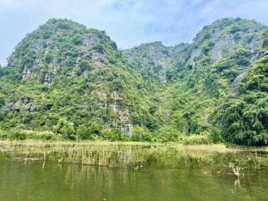 Verimli yeşil bitki örtüsüyle kaplı kireçtaşı kayalıkları Vietnam 'da muhteşem ve görkemli bir doğal manzara yaratıyor. Birbiri üzerine yığılmış kireçtaşı katmanları milyonlarca yıl süren jeolojik oluşum sürecine tanıklık eder.