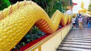 Turistler Pattaya 'daki Büyük Buda Tapınağı' nda altın Buda heykeline ibadet etmek için ejderha merdivenlerinde yürüyorlar. Video, tepeye çıkan altın Naga ejderhalarıyla çevrili yüksek basamakları tırmanan turistleri çekiyor.