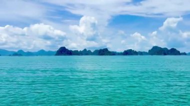 Bulutların panoramik görüntüsü ve feribotun güvertesinden Co To 'ya mavi deniz suyu. Uzakta sisli kireçtaşı dağları olan sakin deniz yüzeyi. Bai Tu Long Bay, Quang Ninh, Vietnam 16 Temmuz 2025. Video bir rahatlama hissi uyandırıyor.