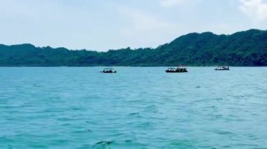 Barışçıl Bai Tu Long Bay Vietnam 'daki koyu yeşil dağların yakınına demir atmış küçük turist tekneleri. Video, adanın kıyılarında yüzen ya da demirleyen yolcu teknelerini gösteriyor. Etrafı görkemli doğayla çevrili. Bai Tu Long Körfezi, Quang Ninh, Vietnam