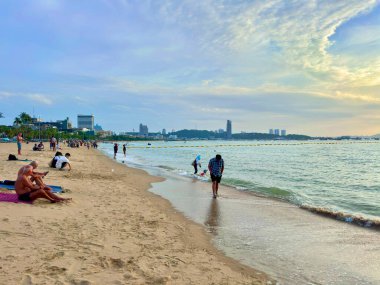 Gökyüzü yavaş yavaş öğleden sonraya dönerken, Pattaya kıyı şeridi boyunca turistik etkinliklerin sahnesi. İnsanlar yürüyor, kumda dinleniyor ve denizden gelen serin esintinin tadını çıkarıyorlar. Pattaya Sahili, Tayland 29 Temmuz 2025.