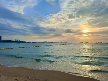 Pattaya Körfezi bölgesindeki deniz suyu yüzeyine parlak bir güneş ışığı yansıyor. Güvenli şamandıralar bulutlu bir gökyüzünün altında mavi parıldayan su arka planına karşı dururlar. Pattaya Sahili, Tayland 29 Temmuz 2025. Sahne bir anlam getiriyor.