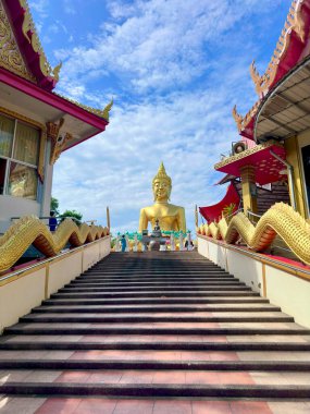 Wat Phra Yai Tapınağı Pattaya 'da dev altın ejder nagalarıyla Büyük Buda heykeline çıkan merdiven. Geniş merdivenlerin alçak açılı görüntüsü. Parlak mavi gökyüzünün altında süslü altın ejderha korkulukları var. Büyük Buda Tapınağı Pattaya, Tayland