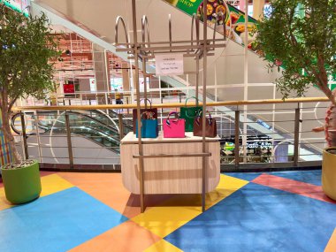 Big C Rajdamri süpermarket Bangkok 'taki yürüyen merdivenin yanındaki lüks moda el çantası tezgahı. İçinde mavi, pembe ve kahverengi zarif tonları olan renkli çantalar olan modern bir büfe. Bangkok, Tayland 29 Temmuz 2025.