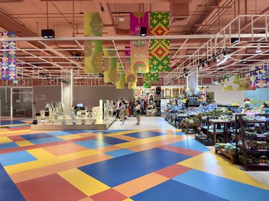 Canlı Tayland kültür afişleri ve renkli döşemeleri olan Büyük C Rajdamri süpermarketinin iç mekanı. Perakende alanının geniş panoramik manzarası tavandan sarkan geleneksel afişler ve geometrik taban desenleri. Bangkok, Tayland