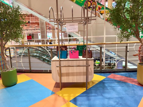 Big C Rajdamri süpermarket Bangkok 'taki yürüyen merdivenin yanındaki lüks moda el çantası tezgahı. İçinde mavi, pembe ve kahverengi zarif tonları olan renkli çantalar olan modern bir büfe. Bangkok, Tayland 29 Temmuz 2025.