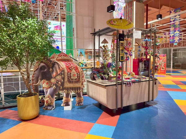 Büyük C Rajdamri süpermarket Bangkok 'ta fil modeli ve dekoratif şemsiyeli Tayland el işi tezgahı. Süslü bir fil modeli ve sarı bir şemsiyenin altında asılı el yapımı tekstil ürünleri olan canlı bir kabin. Bangkok, Tayland