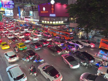Geceleyin Bangkok caddesindeki Ejderha Deniz Ürünleri restoranının önünde çeşitli araçlar birbirine dolandı. Görüntü lüks arabalardan renkli taksilere, motosikletlere ve ikonik turuncu otobüslere kadar olan çeşitliliği kaydediyor. Bangkok, Tayland 'da yakalandı.