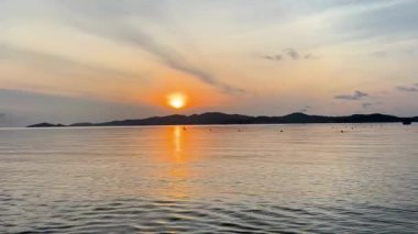 Altın güneşin yükselişine yaklaş ve sakin deniz yüzeyindeki suya parlak ışığı yansıt. Kamera, 20 Temmuz 2025 'te, Hong Van Sahili' ndeki Coto Island, Quang Ninh, Vietnam 'da denizin hafif dalgalanmalarına odaklanıyor.