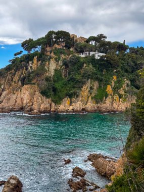 Mediterranean Sea, rocky coastline, clear turquoise water, landscape with trees, houses on the shore