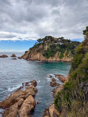 Mediterranean Sea, rocky coastline, clear turquoise water, landscape with trees, houses on the shore