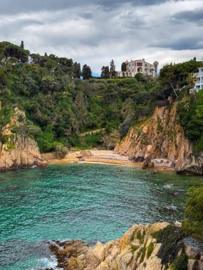Mediterranean Sea, rocky coastline, clear turquoise water, landscape with trees, houses on the shore