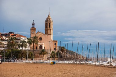 Sitges, İspanya, 6 Kasım 2025: Yaşlı bir kadın alışveriş arabasıyla sokakta yürüyor. İspanya 'da günlük hayatı, ayak işlerini ve kentsel yaşam tarzını gösteren editoryal resim.