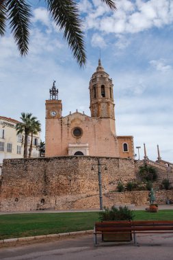 Sitges, İspanya, 6 Kasım 2025: Yaşlı bir kadın alışveriş arabasıyla sokakta yürüyor. İspanya 'da günlük hayatı, ayak işlerini ve kentsel yaşam tarzını gösteren editoryal resim.