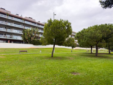 Sitges, İspanya Ocak 2026 Konut kompleksi birden fazla katlı ve ağaçlı yeşil çimlerin arkasında geniş teraslı. Modern şehir konutları ve Akdeniz mimarisi.