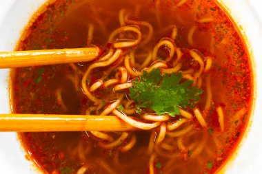 Baharatlı hazır şehriye, kişniş yaprakları, baharatlar ve plastik bardakta yemek çubukları..