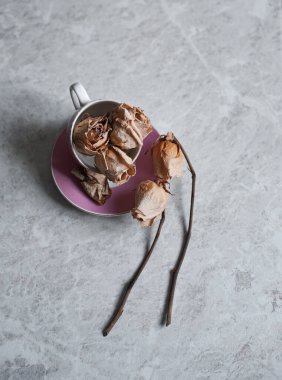 Hafif arka planda solmuş güller. Pembe bardakta kurumuş güller.