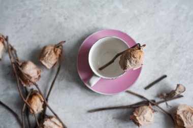 Hafif arka planda solmuş güller. Pembe bardakta kurumuş güller.