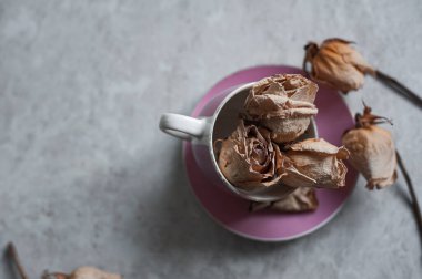 Hafif arka planda solmuş güller. Pembe bardakta kurumuş güller.