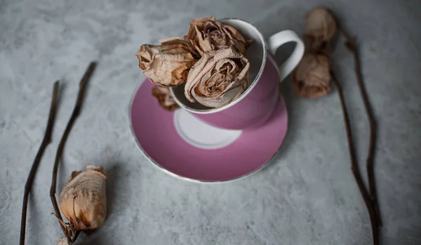 withered roses on a light background. Dried roses in a pink glass