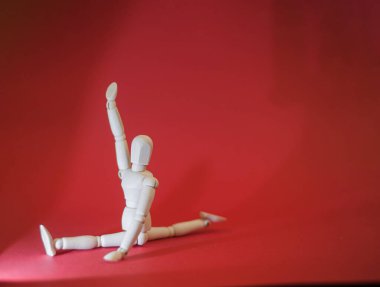 Ahşap adam kırmızı bir zemin üzerinde bir ışık demetinde sicim üzerinde oturuyor