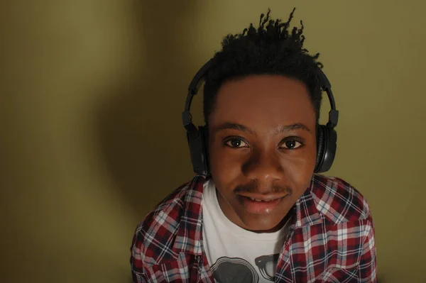 헤드폰을 끼고 녹색 배경을 가진 젊은 아프리카계 미국인 — 스톡 사진