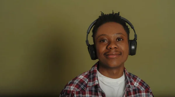헤드폰을 끼고 녹색 배경을 가진 젊은 아프리카계 미국인 — 스톡 사진
