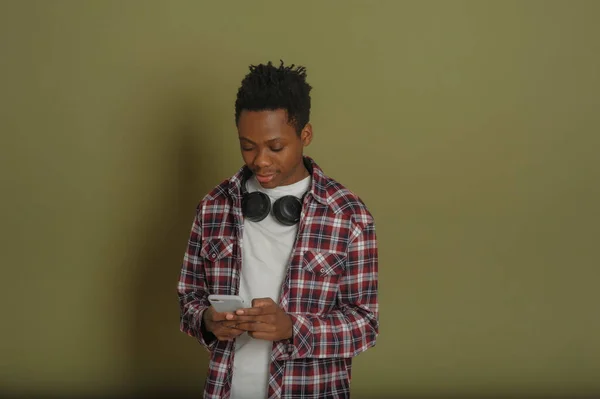 Ung afrikansk amerikan kille talar i telefon på en grön bakgrund — Stockfoto