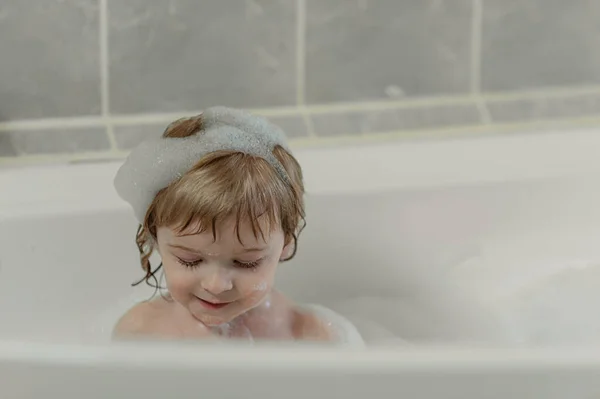 Petit enfant souriant s'assoit dans un grand bain moussant. Vue d'en haut. Flatley Photos De Stock Libres De Droits